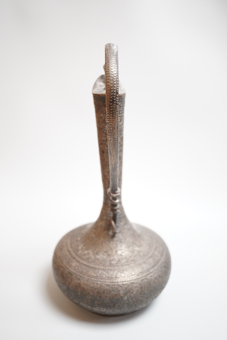 A late 19th century Indian white metal ewer, with extensive foliate decoration and cobra handle, height 30.3cm.